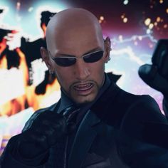 a bald man wearing sunglasses and a black jacket pointing his finger at something in front of him