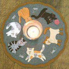 a rug with cats on it and a candle in the middle, sitting on a wooden floor