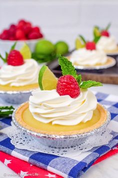 two pies with whipped cream and raspberries on top are sitting on a table