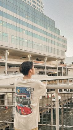 a young man standing on top of a bridge next to a tall building with windows