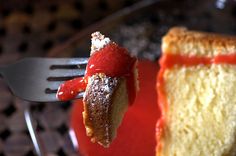 a piece of cake is being held up by a fork with strawberry sauce on it