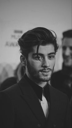 black and white photograph of a man wearing a suit with his hair pulled back in a bun