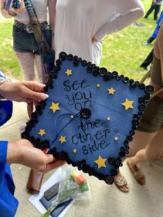 someone holding up a graduation cap that says see you on the other side with stars