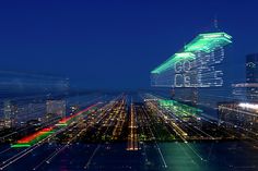 an aerial view of a city at night with skyscrapers lit up in green and red