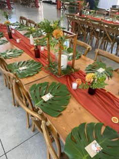 the table is set up with many different plants and candles on it, along with place settings for guests to sit at