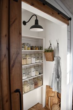 an open pantry door with jars and baskets on it, hanging from the ceiling above