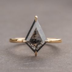 a gold ring with a black and white diamond in the shape of an inverted triangle