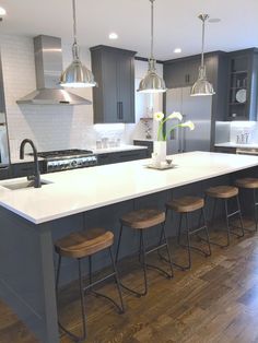 a large kitchen island with stools next to it and lights hanging from the ceiling