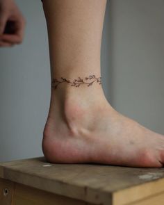 a woman's foot with a small tattoo on the side of her leg,