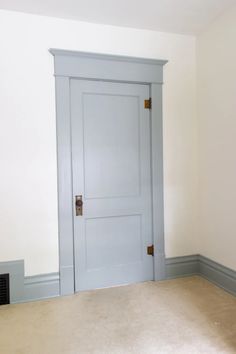 an empty room with a blue door and carpeted floor in front of white walls