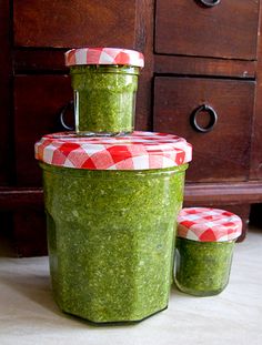 three jars filled with green food sitting on top of a floor next to a dresser