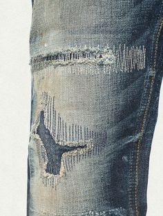 the back pocket of a pair of jeans with holes and torn up patches on them