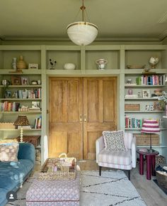 a living room filled with furniture and bookshelves next to a wooden front door