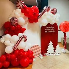 red and white balloons are hanging from the wall near a christmas tree with candy canes