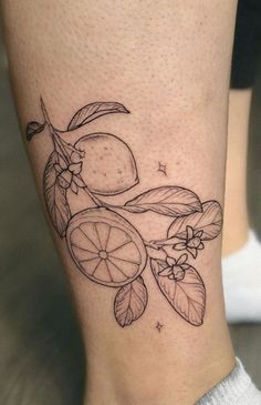 a tattoo on the leg of a woman with lemons and leaves