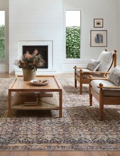 a living room with two chairs and a coffee table in front of a fire place