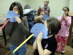 several children holding up paper cutouts to look like an elephant in front of them