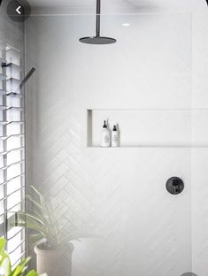 a bathroom with a shower head and white tile walls