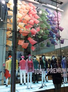 there are many different colored umbrellas in the store window and one is on display