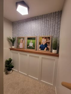 three framed pictures on the wall above a shelf in a room with white walls and beige carpet