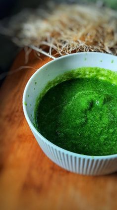 a white bowl filled with green liquid on top of a wooden table