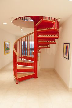 a red spiral staircase in an empty room