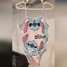 a pink and blue one piece swimsuit with stitch on it hanging from a rack