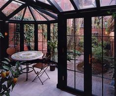 a table and chairs in a room with glass walls that look like they have been built into the ground