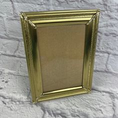 a gold frame sitting on top of a white brick wall