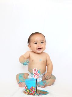 a baby is sitting on the floor with cake and sprinkles all over his body