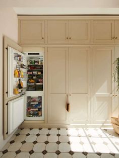 an open refrigerator in the middle of a kitchen with tiled flooring and white walls