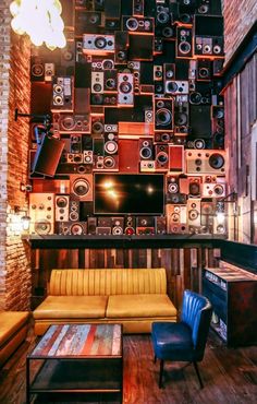 a living room filled with furniture and lots of sound equipment on the wall above it