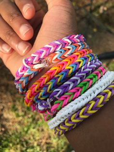 a person holding several different colored bracelets in their hand and wearing one on the wrist