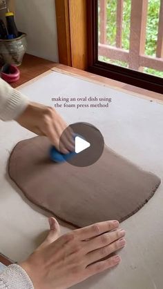 a person is using a sponge to make an oval dish using clay and paper towel