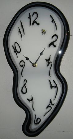 a white clock with black numbers on it's face is hanging from the wall