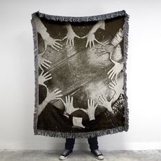 a person standing in front of a black and white photo holding a blanket with hands on it