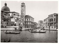 black and white photograph of gondolas on the water in front of old buildings