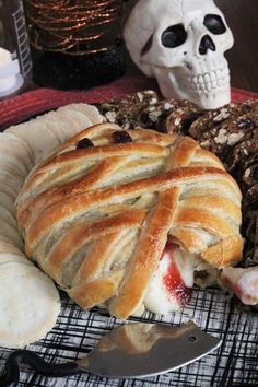 a plate with bread and other food on it next to a skull head, fork and knife