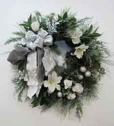 a christmas wreath with white flowers and greenery