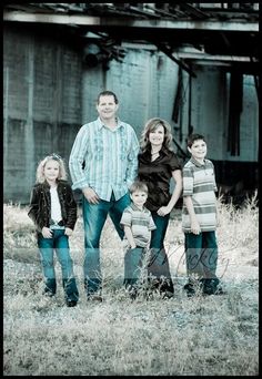 the family is posing for a photo in front of an old building and grain silo