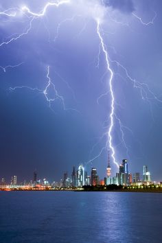 lightning strikes over the city skyline and water