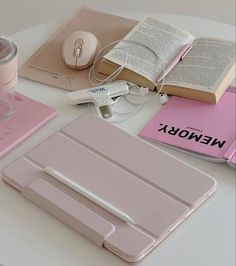 a table topped with pink notebooks and other items next to a cup of coffee