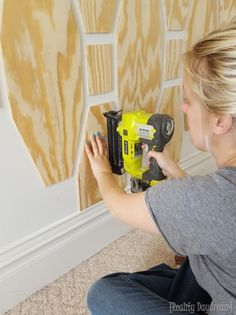 a woman is using a drill to paint the wall