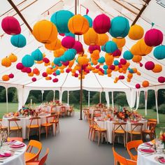 an outdoor tent with tables and chairs covered in colorful paper lanterns hanging from the ceiling