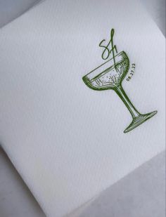 a white napkin with a green design on it and a wine glass in the middle