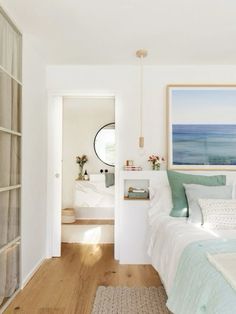 a bedroom with white walls and wood flooring next to a bed in front of a painting on the wall