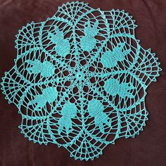 a crocheted doily is shown on a brown surface with blue thread in the center