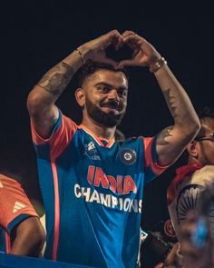 a man making a heart shape with his hands while standing in front of other people