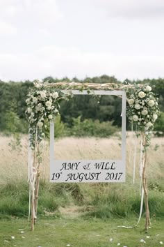 a wedding arch decorated with white flowers and greenery for an outdoor ceremony in the countryside