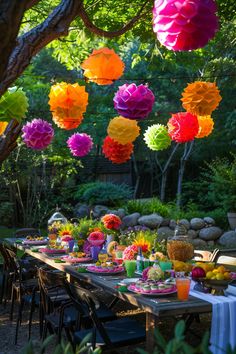 a long table with many colorful paper lanterns hanging from it's ceiling over it